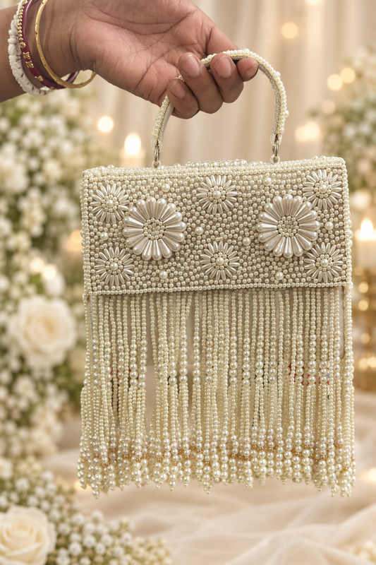 AI styling illustration of Amy Clutch with ivory floral beadwork and pearl fringe against a cream wedding backdrop.